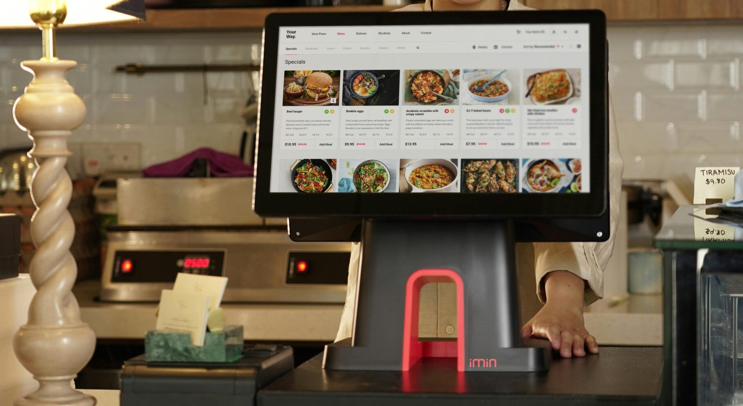 A cashier uses a touchscreen system for taking orders in a restaurant setting.